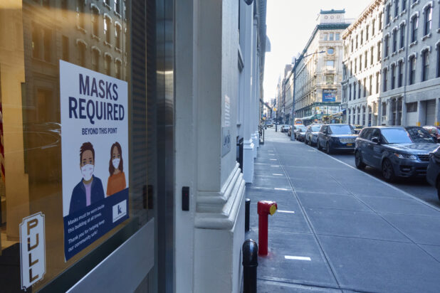 View Down an Empty Street with a Store Front Showing a Masks Required Sign During Lockdown in New York City