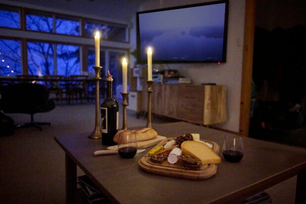A Candlelit Spread of Cheese, Crackers and Bread with a Bottle of Red Wine in a Living Room Setting