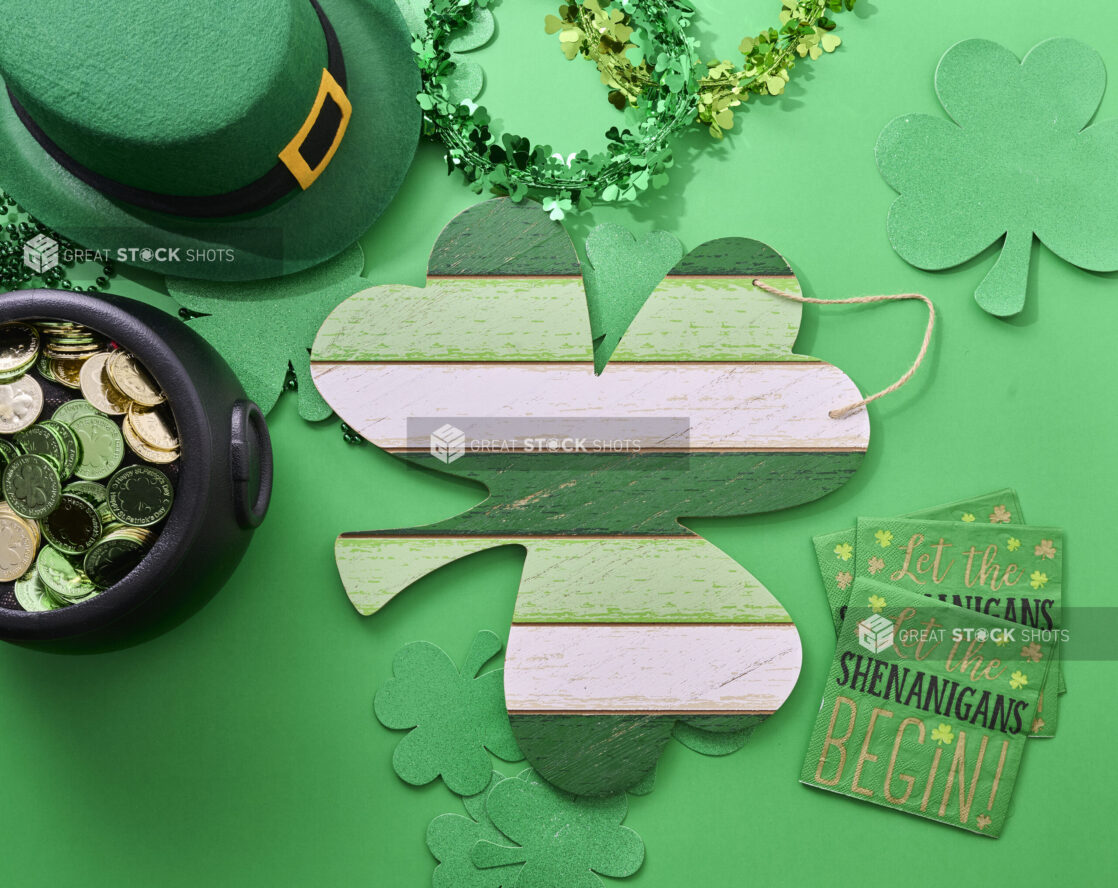 Overhead View of a Painted Wood Shamrock Sign Surrounded by St. Patrick's Day Decorations on a Green Background