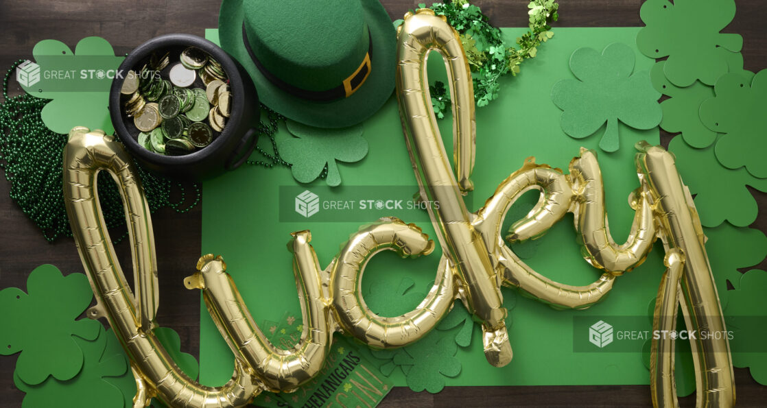 Overhead View of a Gold “Lucky” Balloon Surrounded by St. Patrick’s Day Decorations on a Dark Wood Surface - Variation