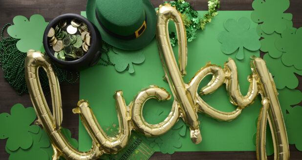 Overhead View of a Gold “Lucky” Balloon Surrounded by St. Patrick’s Day Decorations on a Dark Wood Surface - Variation