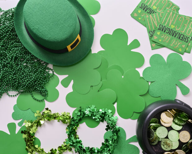 Overhead View of an Assortment of St. Patrick’s Day Decorations – Shamrock Wreaths, Leprechaun Hat, Green Clover Clings and a Pot of Gold - Variation