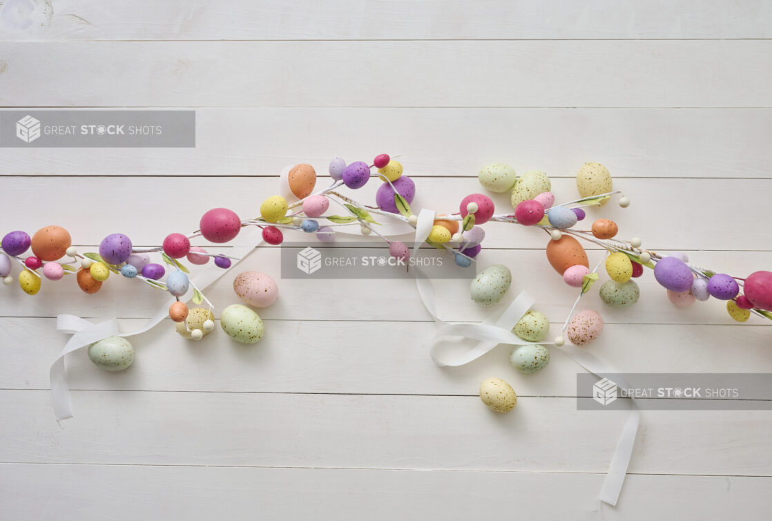 Overhead View of an Easter Egg Garland and Pastel-Coloured Easter Eggs on a White Painted Wood Table