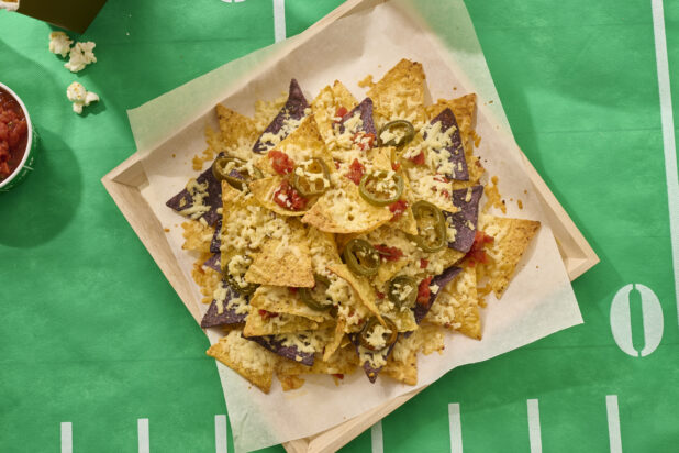 Close Up Overhead View of a Nacho Platter on a Square Wood Tray on a Football Field Table Cloth