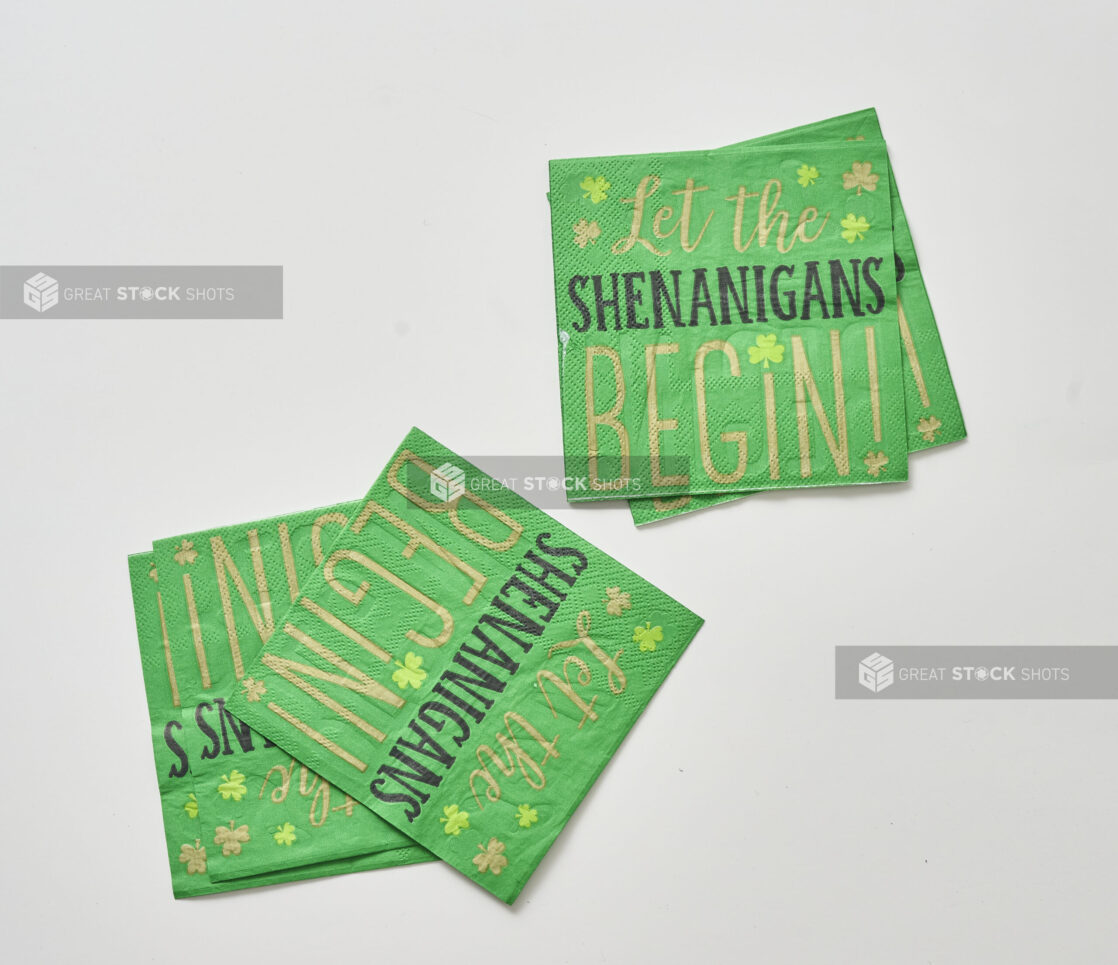 Green Paper Napkins with the Slogan "Let the Shenanigans Begin" for St. Patrick's Day Celebrations, Shot on White for Isolation