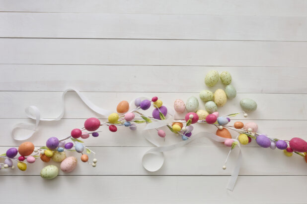 Overhead View of an Easter Egg Garland and Pastel-Coloured Easter Eggs on a White Painted Wood Table - Variation