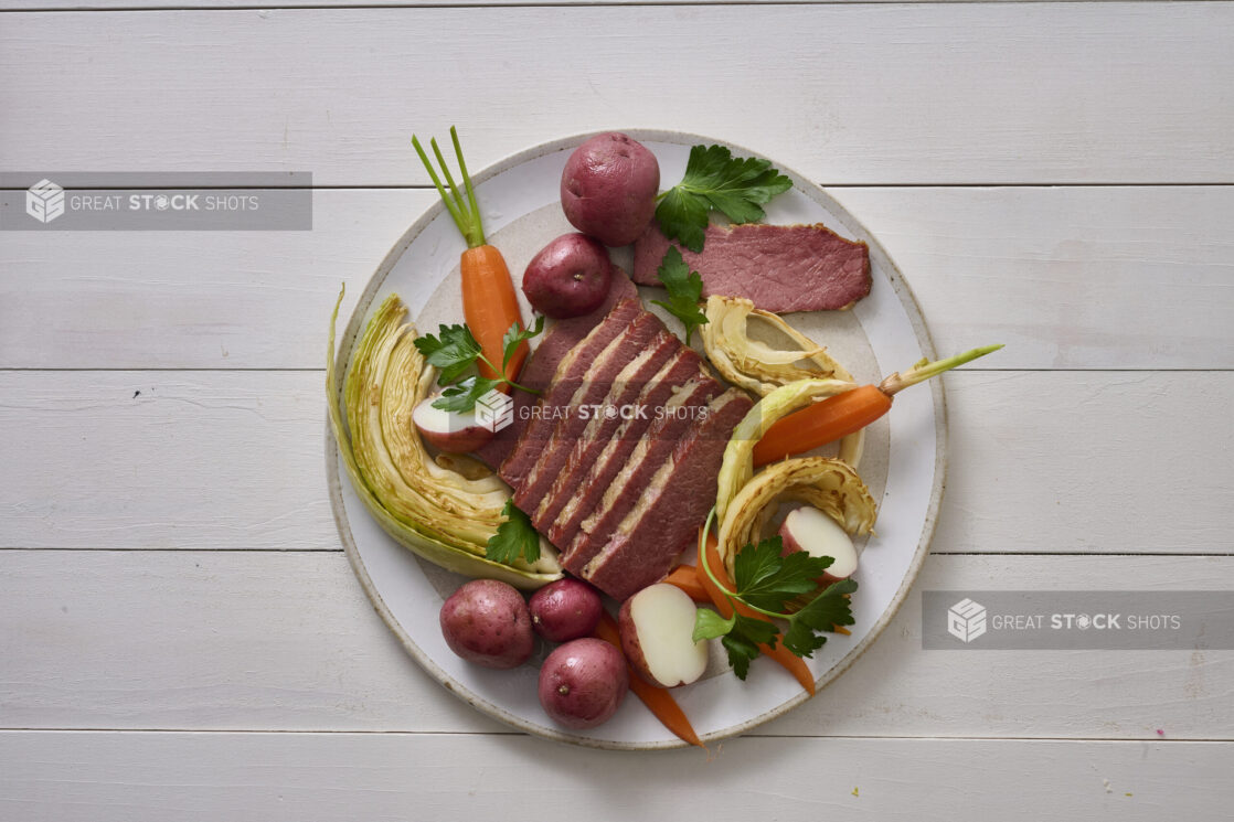 Overhead Shot of a Plate of Corned Beef and Cabbage, Carrots and Red Skinned Potatoes on a White Painted Wood Table