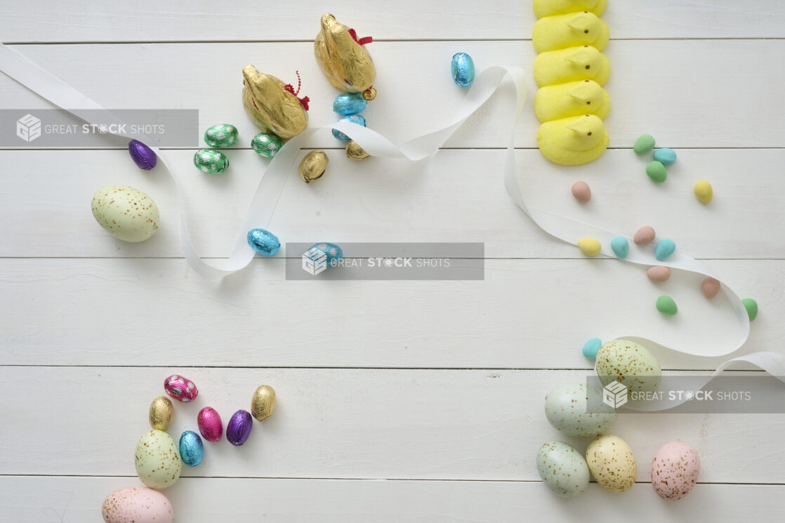 Overhead View of Assorted Chocolate Easter Eggs and Easter-Themed Sweets on a White Painted Wood Table