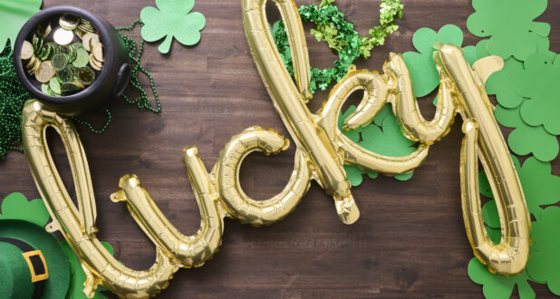 Overhead View of a Gold "Lucky" Balloon Surrounded by St. Patrick's Day Decorations on a Dark Wood Surface