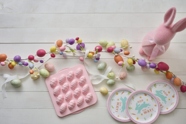 Overhead View of Easter Egg Decorations, Party Plates and a Pink Easter Egg Chocolate Mold on a White Painted Wood Table - Variation