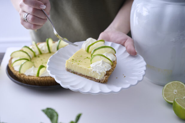 Person Holding a Plate of Key Lime Pie Slice in an Indoor Setting
