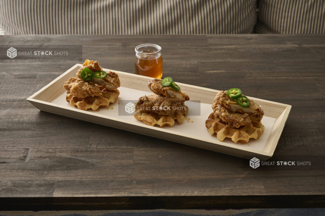 Trio of Fried Chicken and Waffles with Jalapeño Pepper Garnish and Honey Drizzle on a Narrow Rectangular Wood Catering Tray - Variation