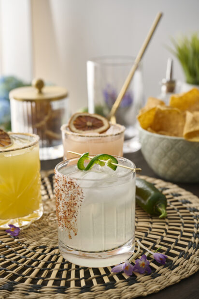 Margarita with Tajin Spice Rim and Jalapeño Pepper Garnish on a Woven Placemat in an Indoor Setting – Sequence 2