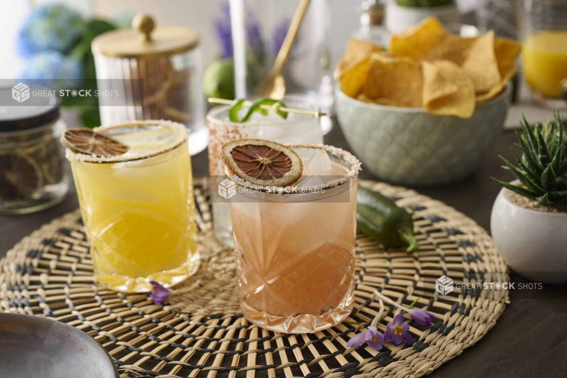 Citrus Margaritas with Dried Fruit Garnish in Glass Tumblers on a Woven Placemat in an Indoor Setting - Variation