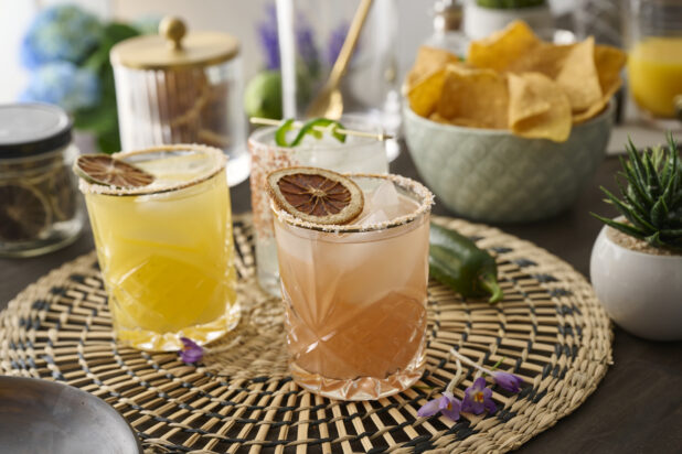 Citrus Margaritas with Dried Fruit Garnish in Glass Tumblers on a Woven Placemat in an Indoor Setting - Variation