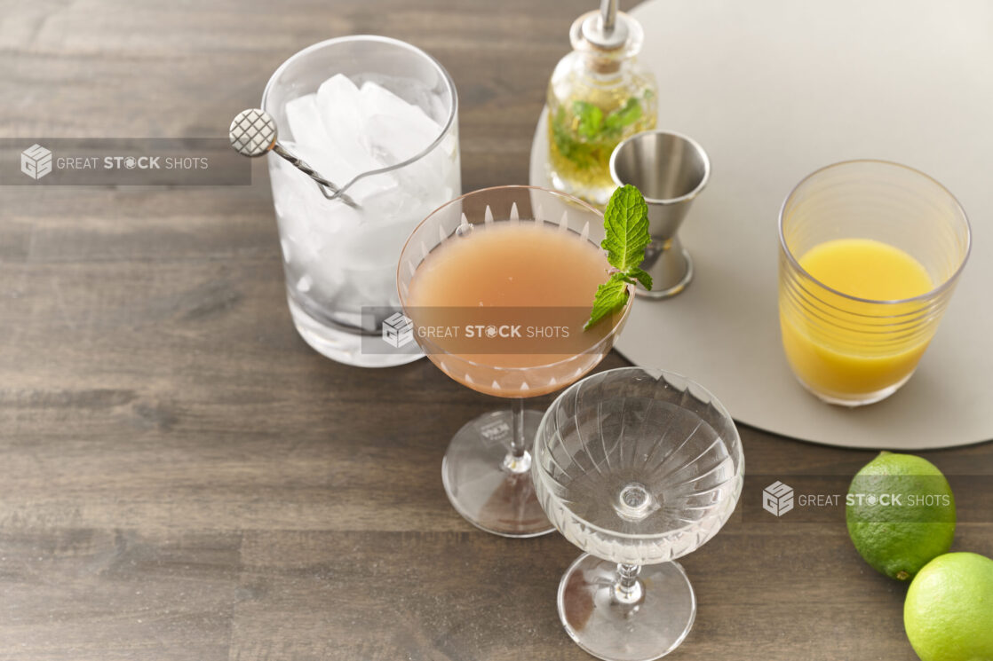 Assorted Cocktails and Cocktail-Making Ingredients with Glassware and Ice on a Dark Wooden Table