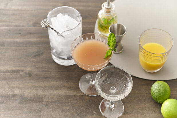 Assorted Cocktails and Cocktail-Making Ingredients with Glassware and Ice on a Dark Wooden Table